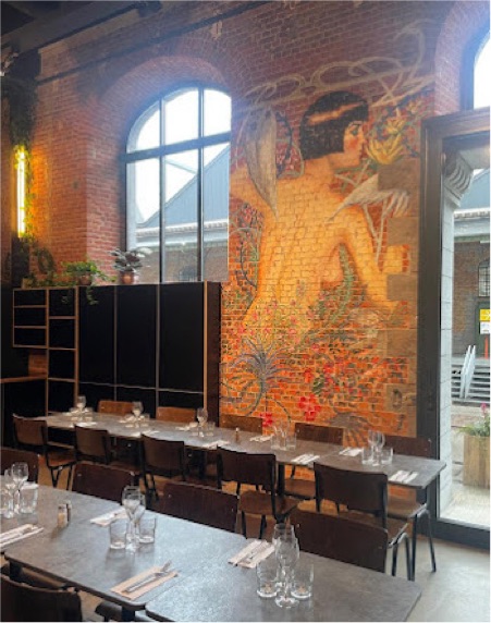 Grande tablée dressée devant la fresque murale et les verrières de L’Annexe